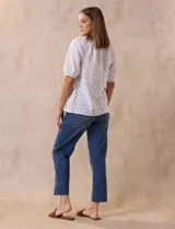 Blusa blanca de tejido calado, marca Sabrina Lauren. Cuello a la base y abertura central con botones.