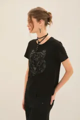 Remera de algodón color negro, con cuello redondo y mangas cortas. Presenta un estampado frontal de un tigre en tonos oscuros y texturas sutiles.