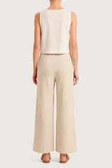 Pantalón de punto color beige, de corte recto y holgado, con cintura elástica y cordón ajustable. Presenta costuras verticales decorativas en el frente.