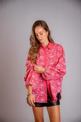 Camisa de manga larga con diseño abullonado, confeccionada en tela bordada con motivos florales. Presenta cierre frontal con botones y puños elásticos.