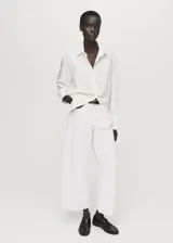 Camisa de lyocell color blanco, con cuello camisero, manga larga con puños abotonados, diseño recto y cierre frontal con botones ocultos.