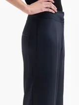 Pantalón negro de viscosa con ligero brillo, estilo babucha, con cintura alta y puños ajustados con elástico en los tobillos. Posee bolsillos diagonales delanteros y ojales traseros.