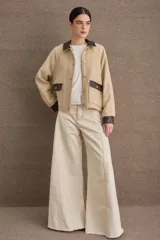 Campera corta de paño color marrón con detalles en cuero sintético al tono en cuello, puños y solapas de bolsillos. Presenta cierre frontal con botones metálicos dorados y dos bolsillos frontales tipo cargo.