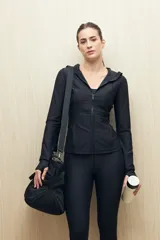 Campera deportiva negra de calce entallado, con cierre frontal completo, capucha integrada y mangas largas con puños envolventes. Presenta costuras estratégicas que estilizan la silueta y bolsillos laterales funcionales.