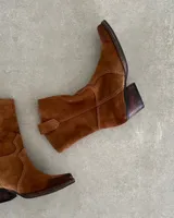 Bota corta estilo western confeccionada en cuero descarne color marrón, con taco cuadrado de madera y punta ligeramente afinada.