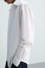 Camisa de corte slim fit con textura, cuello italiano y manga larga con puños abotonados. Presenta cierre frontal con botones.