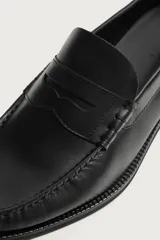 Mocasín de vestir para hombre fabricado en piel de color marrón oscuro, con detalle de antifaz en el empeine y suela con ligero tacón.