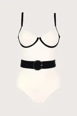 Traje de baño entero blanco con breteles finos negros, escote corazón con borde negro y cinturón negro con hebilla redonda.