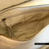 Bandolera de cuero color beige con correa ajustable y cierre superior con cremallera.