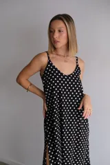 Vestido largo de crepe con estampado de lunares negros sobre fondo blanco. Presenta un diseño de corte holgado con breteles finos y escote redondeado.