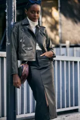 Campera corta color verde oliva de cuero sintético con cuello clásico, cierre frontal asimétrico con cremallera, bolsillos con cremallera y solapa, y detalles de costuras en los hombros.