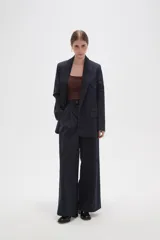 Blazer de corte holgado con diseño de rayas verticales, cuello solapa y cierre frontal con un botón. Presenta bolsillos laterales con solapa y mangas largas.