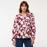Blusa de corte fluido y holgado con estampado floral en tonos bordó y crema. Presenta cuello camisero, cierre frontal con botones y mangas largas con puños rectos.