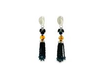 Pendientes colgantes plateados con diseño texturizado en la parte superior, cristales facetados negros y dorados, y una borla de cuentas negras con detalles azules en las puntas.