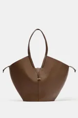Bolso de hombro estilo capazo, color marrón, con doble asa de hombro y cuerpo con pespuntes. Presenta un cierre mediante pasador con clip metálico y una bolsa interior extraíble con cierre fruncido.
