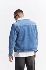 Campera de jean con interior de corderito, cuello clásico y cierre frontal con botones metálicos. Presenta un diseño de denim azul con costuras reforzadas y bolsillos laterales.