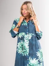 Vestido camisero largo con estampado floral en tonos rojos y negros, con cuello camisero, abotonadura frontal y mangas largas con puños abotonados.