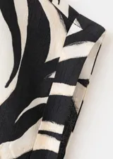 Camisa de manga corta con estampado de hojas en blanco y negro, cuello camisero y cierre delantero con botones.