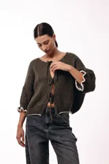 Saco de punto gris con frente abierto, cierre mediante lazos frontales y mangas con puños elásticos. Presenta una textura suave y un diseño de volumen holgado.