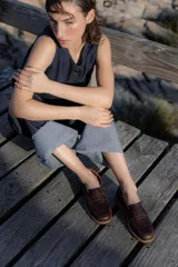 Mocasines negros de cuero con textura tipo cocodrilo en la parte superior y acabado brillante. Presentan una banda frontal clásica y una suela plana con detalle de borde en color natural.