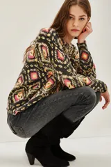 Sweater de punto con cuello redondo y manga larga, estampado en tonos oscuros con motivos geométricos y florales en rosa, amarillo y verde.