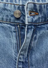 Pantalón de jean celeste de corte wide leg, tiro medio, con pinzas delanteras y bolsillos laterales. Cierre frontal con cremallera y botón.