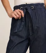 Pantalón baggy de jean azul oscuro, de tiro alto con cintura elástica fruncida y lazo para ajuste. Presenta bolsillos laterales y dobladillos con vuelta en los tobillos.