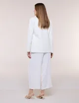 Blazer sastrero blanco de corte recto y estructura entallada, con cuello de solapa en pico, cierre frontal de un botón y bolsillos con solapa.