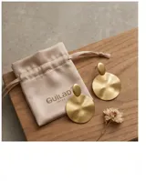 Caravanas de diseño circular con acabado en tono dorado, compuestas por un elemento superior ovalado y un disco inferior de gran tamaño con superficie cóncava.