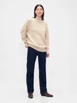 Buzo de algodón color beige con cuello polera, manga larga y diseño holgado con puños y dobladillo en rib.