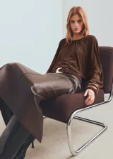 Blusa de color marrón chocolate con cuello redondo, diseño fruncido en la parte superior y mangas largas abullonadas con puños elásticos.