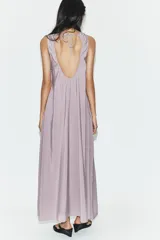 Vestido midi de corte fluido y diseño minimalista, con cuello redondo y mangas sisa. Presenta una abertura en la espalda con cierre y lazada ajustable.