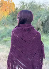 Ruana tejida en crochet color bordó, con diseño de calados horizontales y terminación con flecos largos en todo el borde inferior.