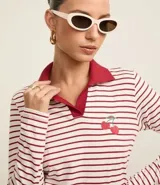 Blusa de algodón a rayas horizontales blancas y rojas, con cuello polo rojo, mangas largas y bordado de cerezas en el pecho.