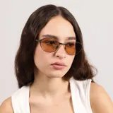 Lentes de sol con marco metálico fino de forma ovalada y cristales en tono ámbar. Cuentan con protección UV400.