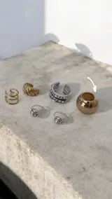 Ear cuff de diseño minimalista y forma esférica, acabado en tono dorado brillante.