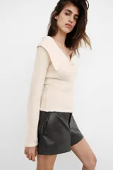 Shorts de tiro bajo confeccionados en material sintético con acabado efecto piel. Presentan bolsillos laterales, falsos bolsillos traseros con solapa y cierre frontal con cremallera, botón interior y gancho metálico.