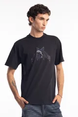 Remera de algodón color negro, con cuello redondo y mangas cortas. Presenta un estampado frontal con una estrella azul y un delfín en el centro, acompañado de tipografía estilo gótico.