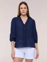 Blusa azul marino de bambula con escote en V y pechera decorada con encaje floral y botones forrados. Presenta mangas tres cuartos abullonadas con inserciones de puntilla y puños elásticos.