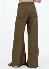 Pantalon de corte recto y pierna ancha, confeccionado en lino color beige. Presenta un diseño de tiro medio con aberturas laterales en el ruedo y detalle de bordes desflecados.