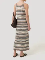Vestido largo de punto con diseño de rayas horizontales onduladas en tonos multicolor, marrón, beige y blanco. Presenta tirantes finos tipo pabilo y escote redondo.