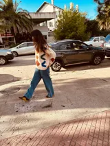 Sweater color crema con bordados geométricos en azul, verde, rojo y marrón. Tiene cuello redondo y mangas largas. Corte holgado.