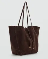 Bolso estilo shopper de piel de serraje color marrón oscuro, con cierre de lazo y botón magnético. Cuenta con doble asa de hombro y bolsillo interior con cremallera.