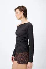 Top blanco elastizado al cuerpo, con cuello recto asimétrico y frunces laterales.