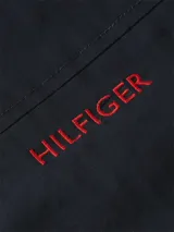 Chaleco azul marino Tommy Hilfiger de cuello alto, con cierre de cremallera frontal, bolsillos laterales de ojal y logo de la marca bordado en rojo en el pecho.