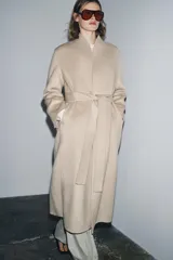Abrigo largo de corte minimalista confeccionado en mezcla de lana, con diseño de solapas integradas, manga larga y cinturón ajustable del mismo tejido.