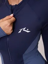 Malla entera de manga larga con cierre frontal, confeccionada en combinación de tonos azul marino y azul medio, con logo de la marca estampado en el pecho.