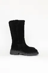 Bota de caña alta confeccionada en cuero negro, con diseño clásico y suela plana con pequeño tacón.