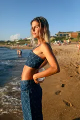 Top corto de denim con escote recto y breteles finos. Presenta un diseño estampado con monograma geométrico en tono azul oscuro.