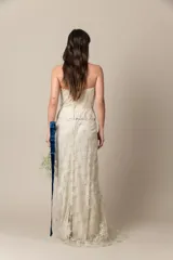 Vestido de novia strapless color natural, confeccionado en tul bordado con corsé drapeado y sobrefalda de tul. Presenta una faja con guarda en la cintura.